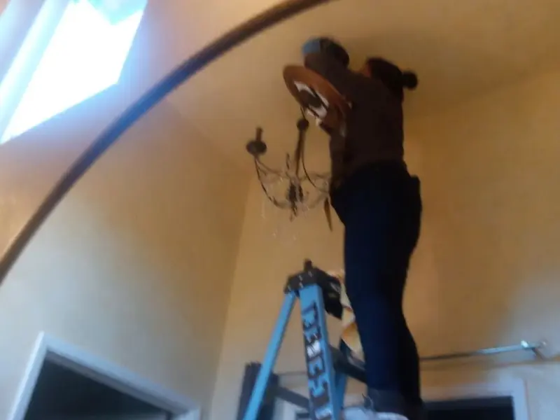 Electrician installing a chandelier in a Harahan residence